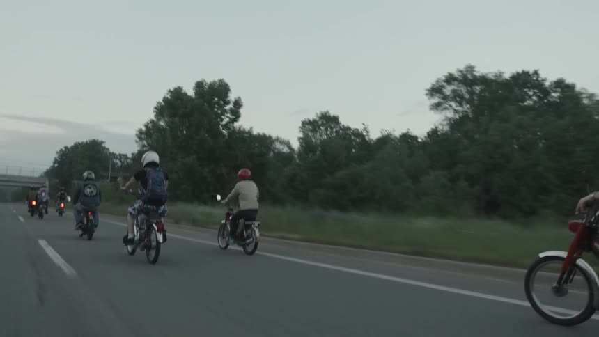 A group of people riding motorbikes down the road