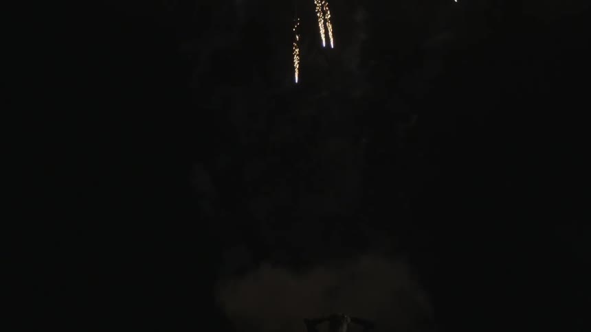 People shoot off fireworks on the beach at night