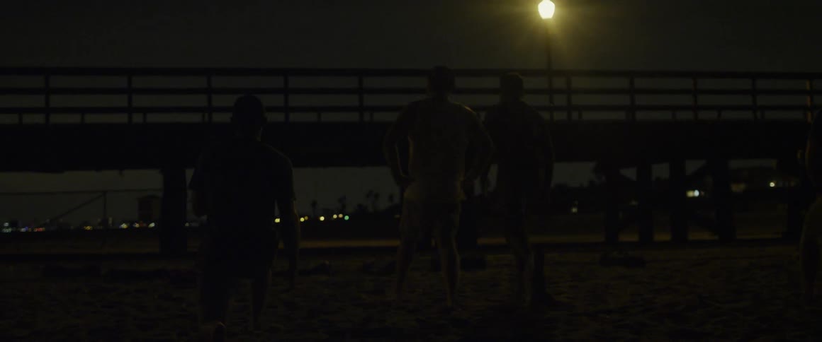 A group of men is exercising on a beach at night