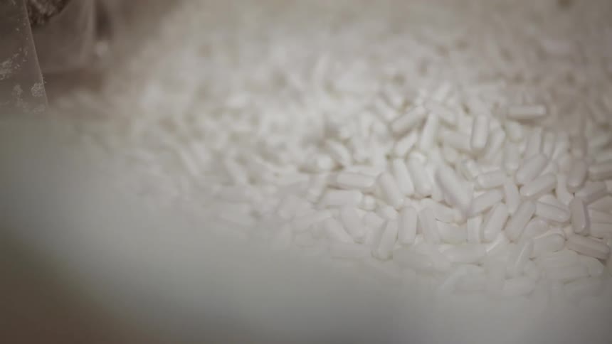 Pills drop into a pile in a bin