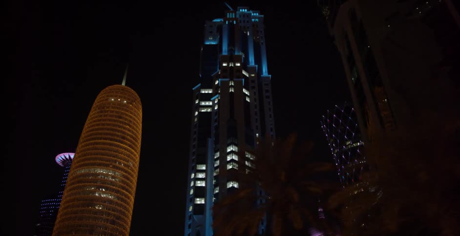 City buildings tower overhead at night