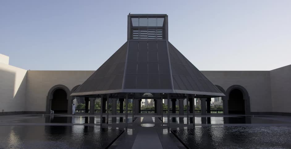 A person walks in a plaza with pools of water and walkways