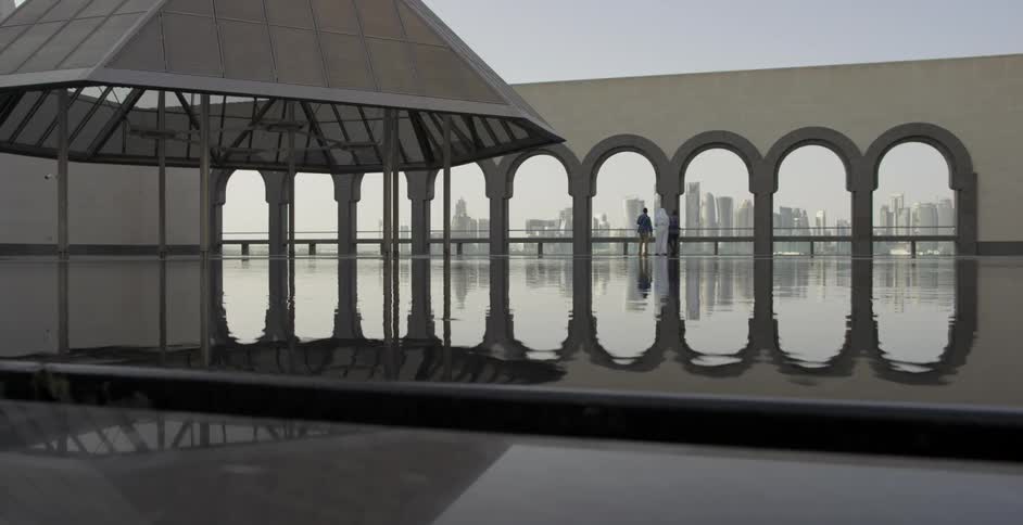 A wall's archways and columns are reflected in a pool of water