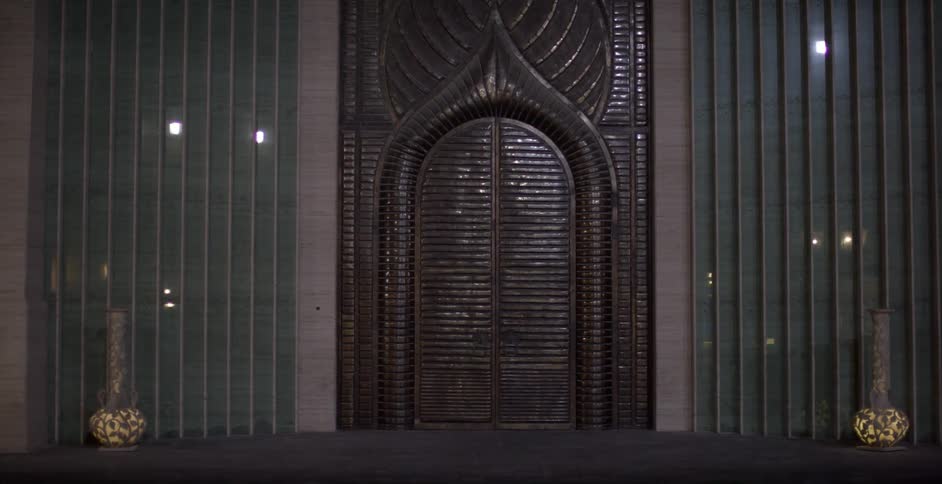 Large vases stand on either side of an arched decorative door