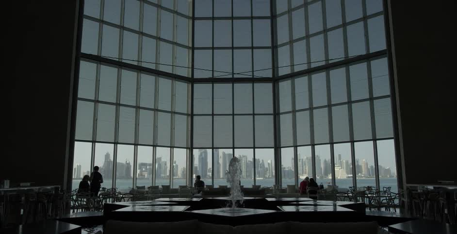 A water fountain gushes inside a building with a city skyline view
