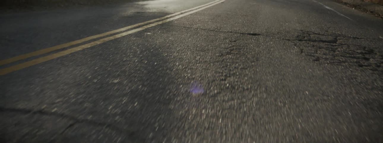 A cracked street turns around a hill