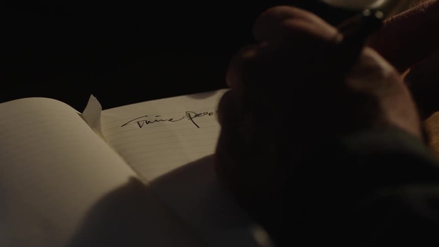 A close view of the pages of a book that someone is writing in