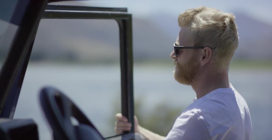 A man exits a vehicle on a sunny day