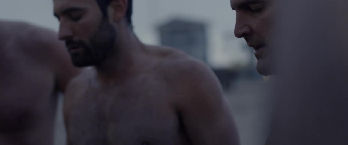 A man on a beach talks to others then claps his hands