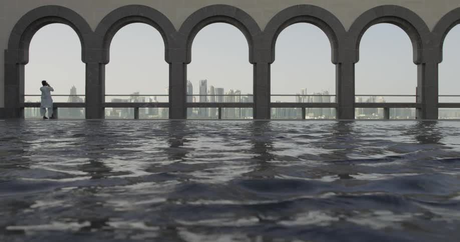 A person stands at a railing beyond a pool of water