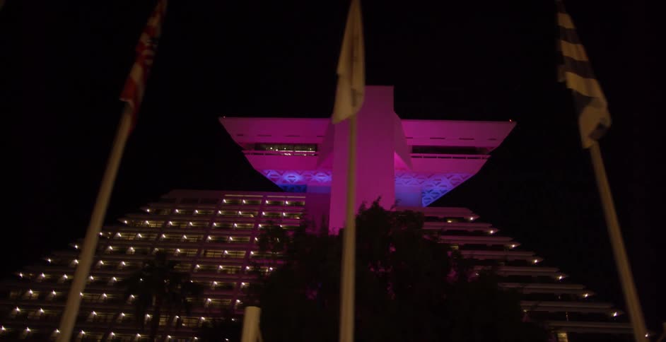 Flags are lined up in front of a city building at night
