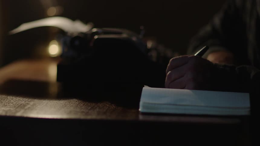 A man writes in a notebook and then types on a typewriter