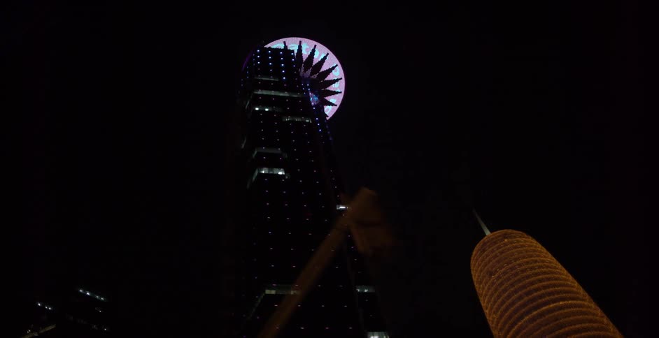 A view of large skyscrapers at night from the ground