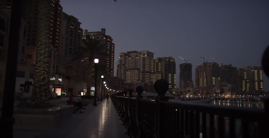 Street lamps light a city walkway near the ocean