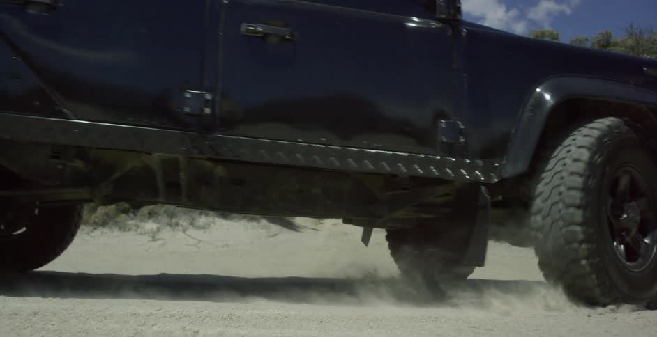 A jeep-style suv is turning on a beach