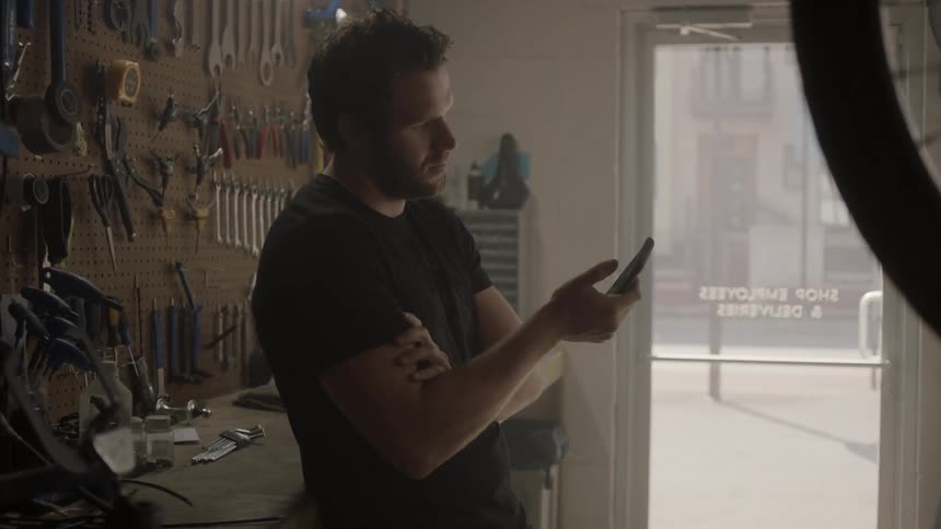 A man scrolls through his phone in a garage