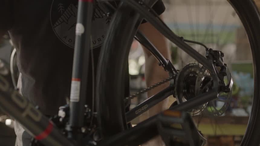 A man is working on a bicycle's wheel in a bike shop