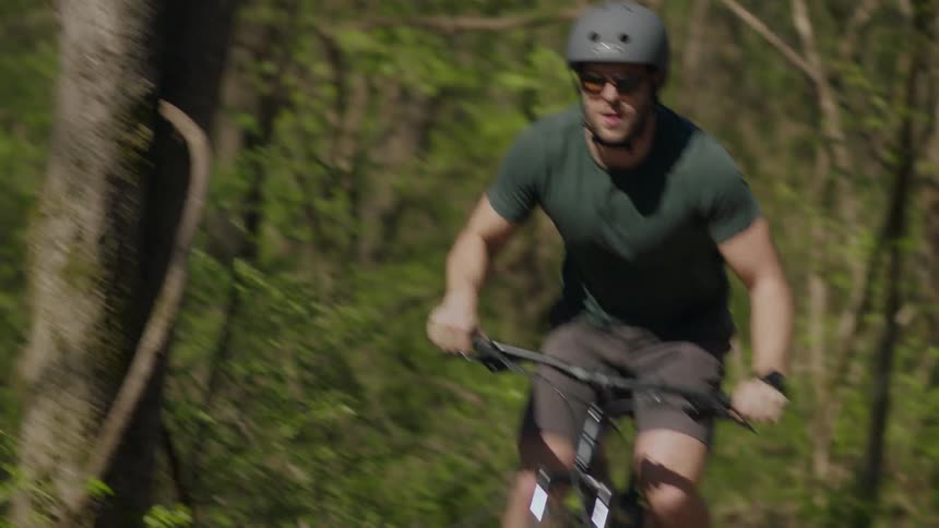 A man is riding a off-road bike on a path in a natural setting
