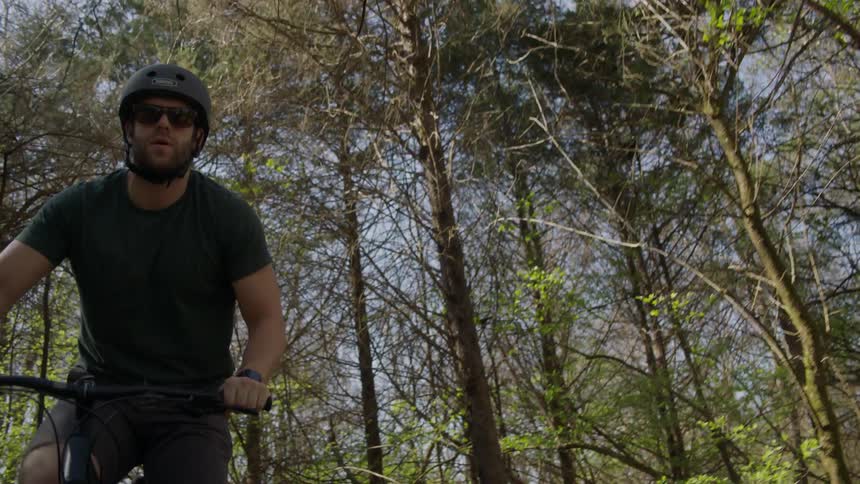 A man wearing a helmet bikes through a forest