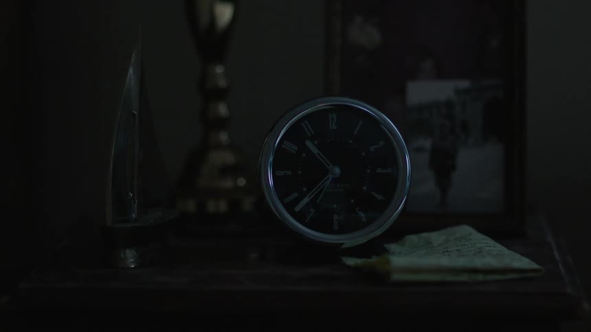 A clock sits on a table in a dark room