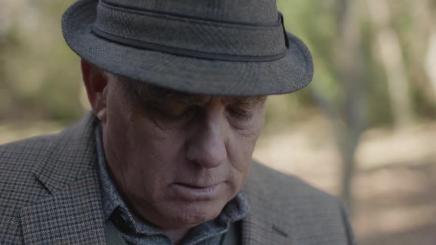 A man in a hat frowns and shakes his head