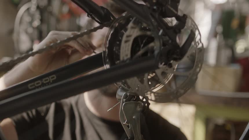 A man works on a bicycle with its tires spinning