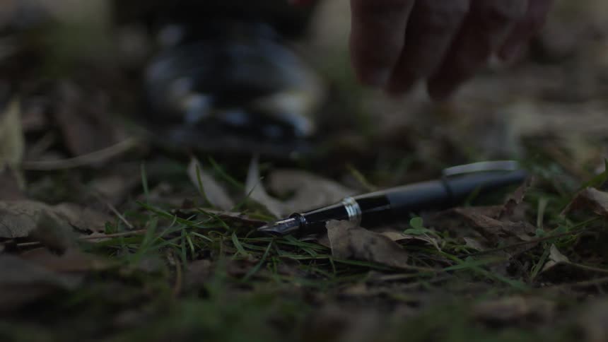 An man picks up a fountain pen from the ground
