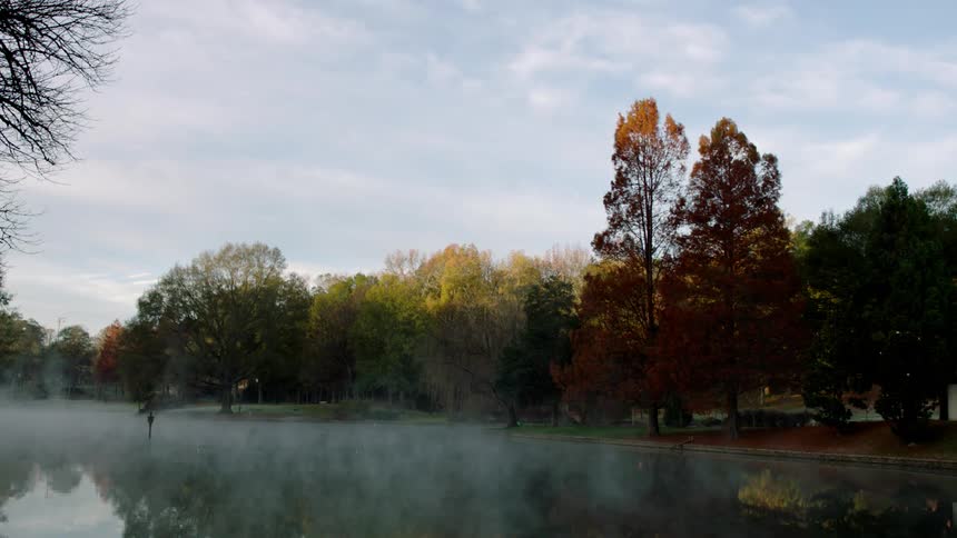 Mist floats over a calm lake in the fall