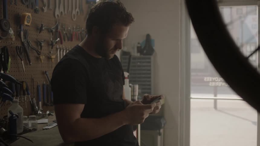 A man stands in a bike shop using his cell phone