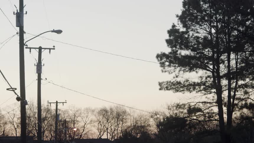 Power lines stretch across a street from poles in a residential area