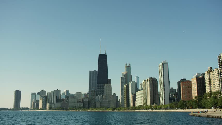 A large body of water ripples in front of skyscrapers