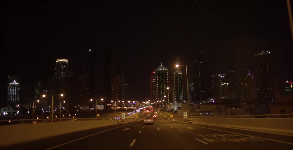 Cars drive on a city street at night