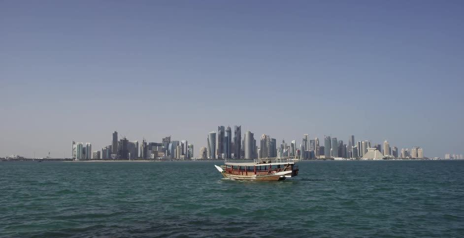 Boat moving slowly on the waters before a very large city on a clear day
