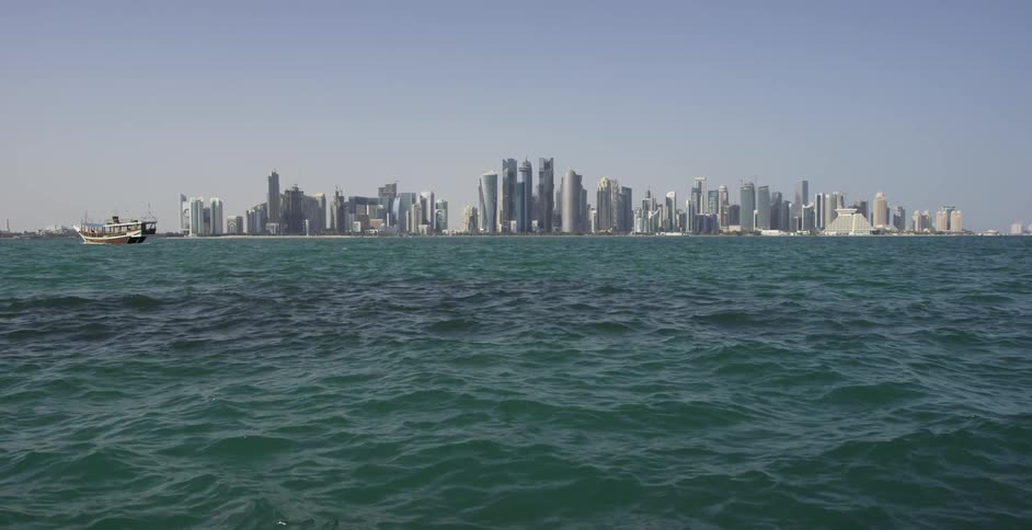 A large body of water ripples and flows with skyscrapers in the distance