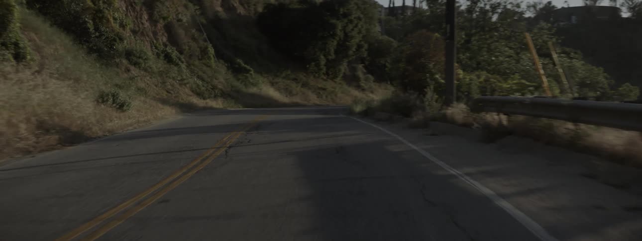 The sun shines on a curving mountain road