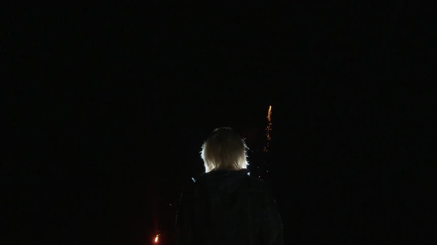A person watches fireworks in the dark