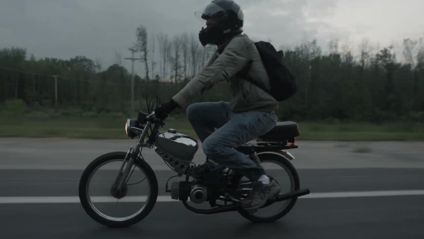 Person riding on a moped on a paved country road