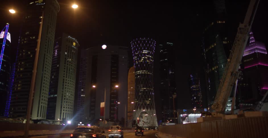A large city with cars driving at night and the skyscrapers lit up