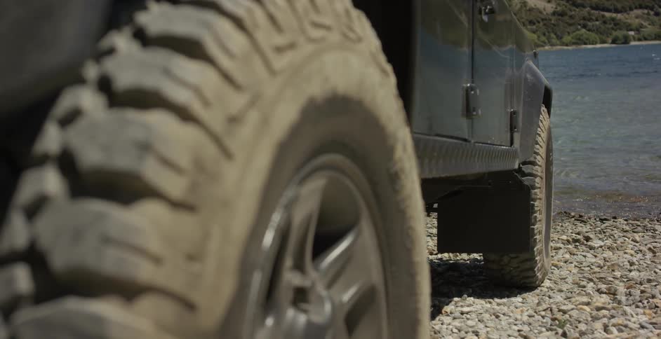 A vehicle with dusty tires near a lake