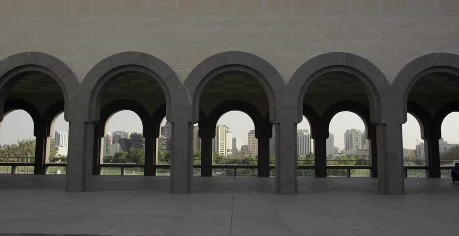 A city in the distance peaks through the arches of a museum building