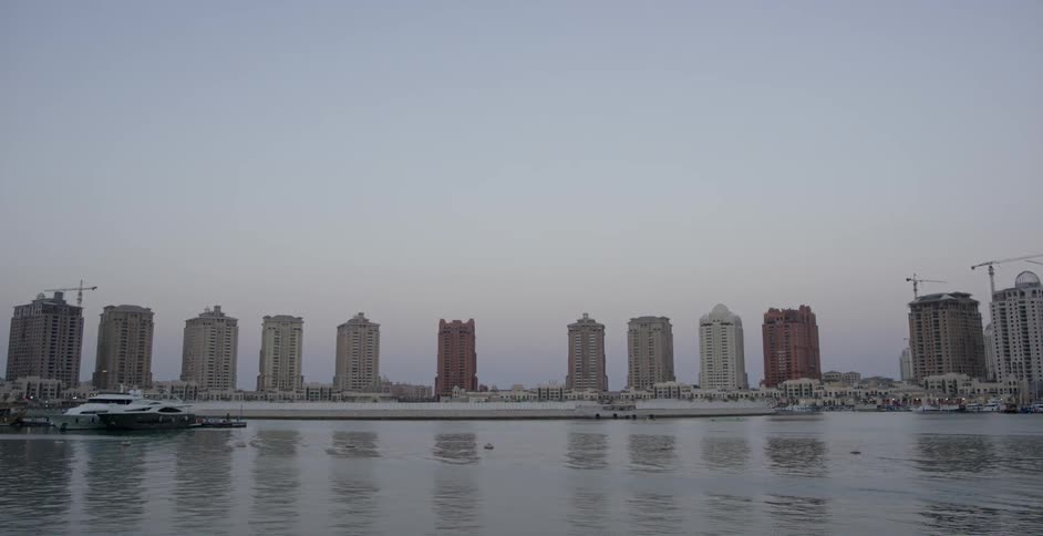 A body of water ripples in front of city buildings