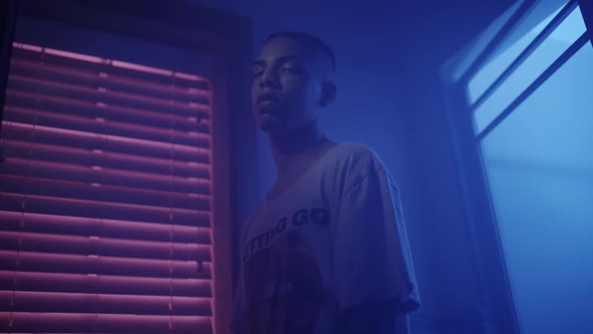 A man stands with his eyes half-closed in a darkened room