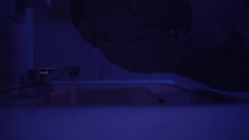 Man washing his face with water in a sink
