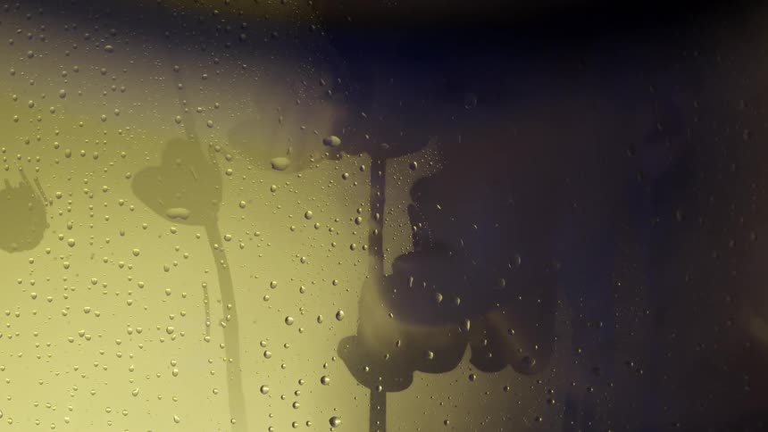Woman looking through a wet steamy pane of glass