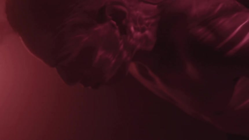 Man floating face down in purple hued water