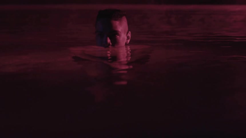 Person floating in purple hued water
