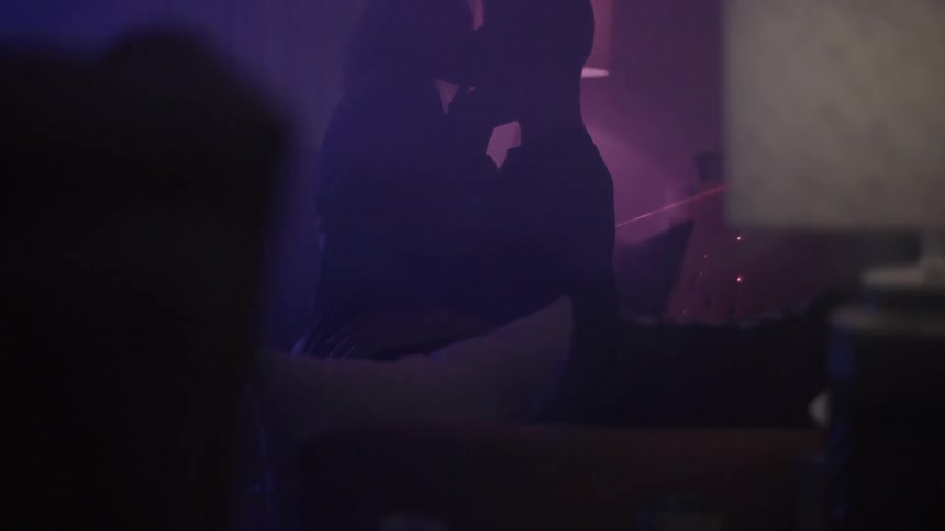 A woman sits in a man's lap as they make out