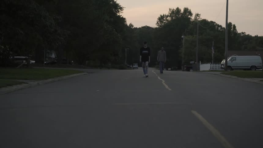 Two boys walk down the middle of a neighborhood road
