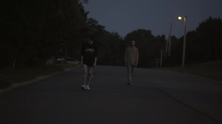 Teenage boys walk on a neighborhood street at night