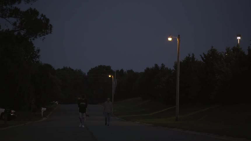 Two teenagers walking down the street at night